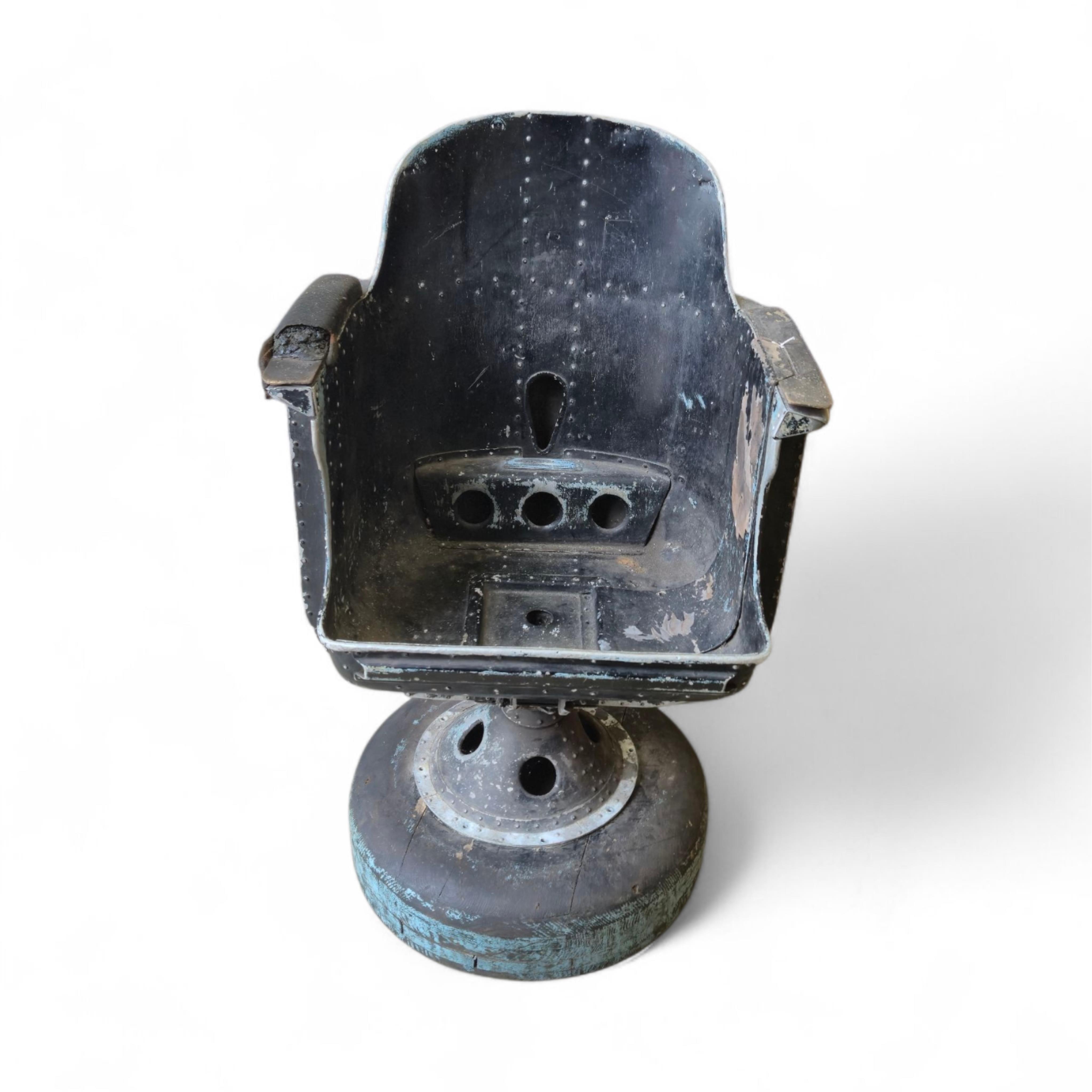 A WWII bomber navigator's chair, with painted aluminium bucket seat and pedestal stand, with a later wooden base, height without base 84cm, the width across the arms 59cm
